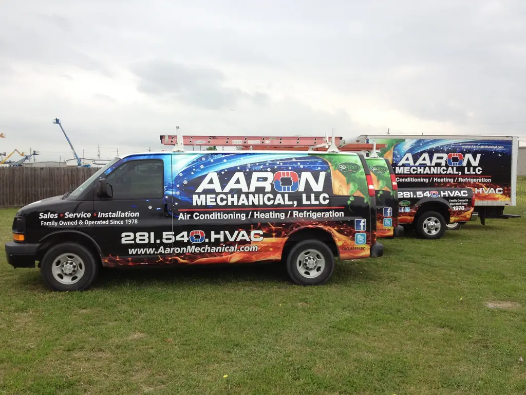 Three wrapped Aaron Mechanical service vehicles parked together