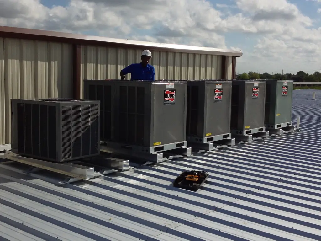 Aaron Mechanical technician behind a row of newly installed RUUD Commercial Series rooftop units